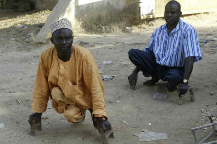 Crippled by polio, two men make their way in Kano, Nigeria, on short crutches. Muslim clergy there had urged a boycott of vaccinations in 2003, saying they were part of a Western plot.
