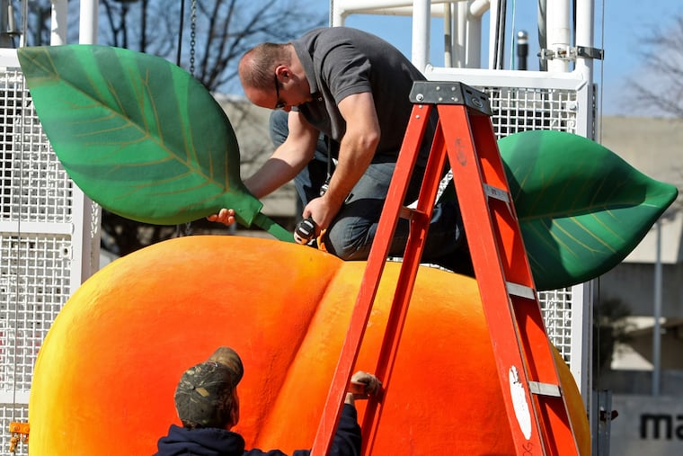 FILE - Gary Seputis, top, and Clint Hornsby, employees of Entertainment Design Group, work on attaching two leaves to the fiberglass and foam Peach in preparation for the 2012 Peach Drop at Underground Atlanta, Friday, Dec. 30, 2011, in Atlanta. ( Jason Getz/Atlanta Journal-Constitution via AP, File)