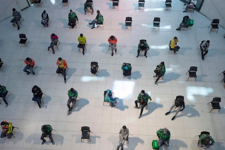 People practice social distancing as they sit on chairs spread apart in a waiting area for take-away food orders at a shopping mall in hopes of preventing the spread of the coronavirus in Bangkok, Thailand.