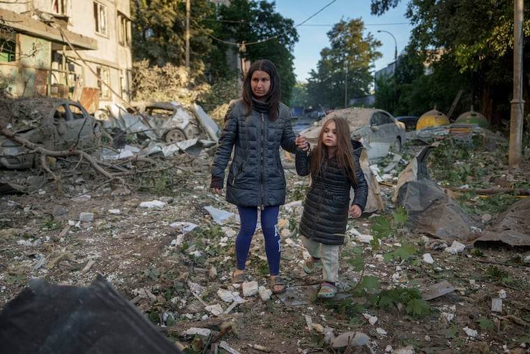 Olga Mudra, 35, and her daughter Natalia, 6, walk in the yard of their house damaged after a Russian strike on Kyiv, Ukraine, on Tuesday, June 2, 2026.