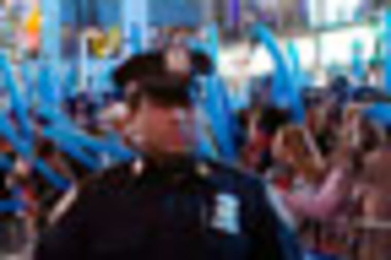 FILE - In this Dec. 31, 2011 file photo, a police officer walks through a frozen zone in New York City’s Times Square as revelers wave balloons in anticipation of midnight. The New York City police use an array of security measures for the event that turns the "Crossroads of the World" into a massive street party in the heart of Manhattan. (AP Photo/John Minchillo, File)
