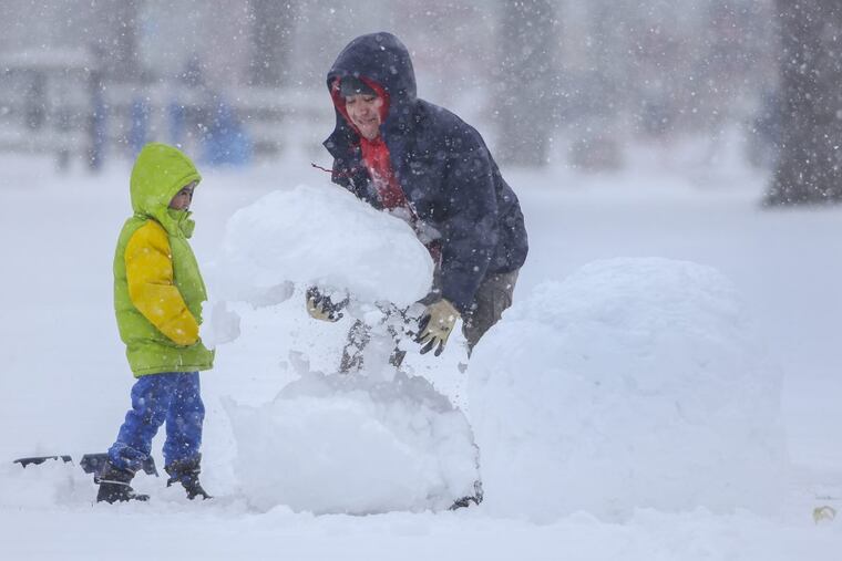 Juan Estrada and his 5-year-old son, Evan, build a snowman in Downingtown on Wednesday, March 21, 2018.
