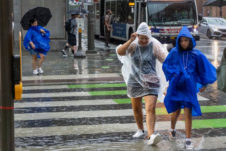 Pedestrians wearing ponchos walk across Fifth and Market Streets in Philadelphia during Tuesday's storms.