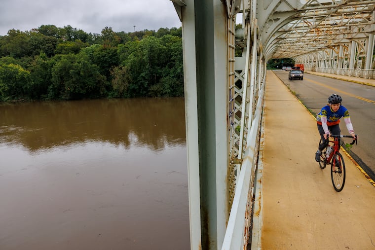 Cyclist riding across the Falls Bridge over theSchuylkill River on Monday in the wake of the Ophelia-related rains. More rain is due Friday.