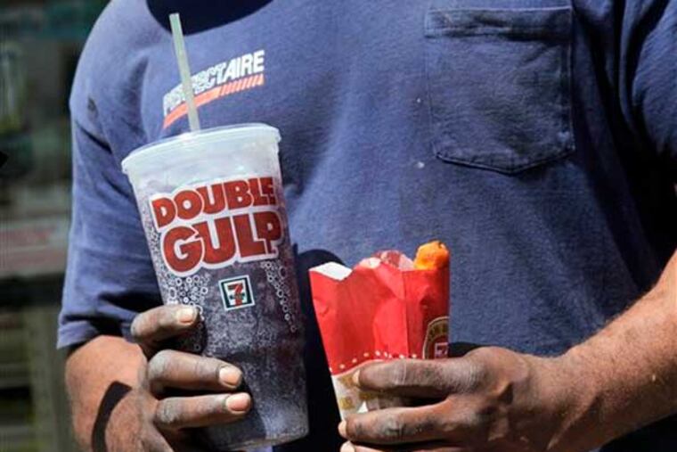 FILE - In this May 31, 2012 file photo, a man leaves a 7-Eleven store with a Double Gulp drink, in New York. Opponents of the city’s limit on the size of sugary drinks are are raising questions of racial fairness alongside other complaints as the novel restriction faces a court test. (AP Photo/Richard Drew, File)