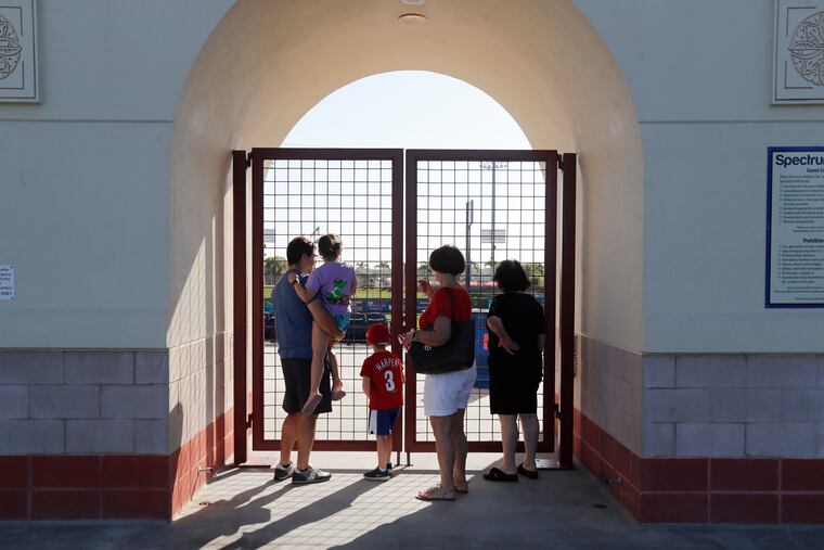 Fans look from outside the gates to Spectrum Field, spring training baseball game home of the Philadelphia Phillies which were locked last Friday.