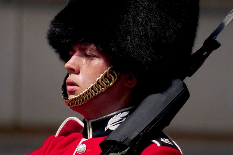 A member of F Company Scots Guards swelters in the heat during the Changing of the Guard ceremony on the forecourt of Buckingham Palace, central London, Tuesday July 19, 2022.