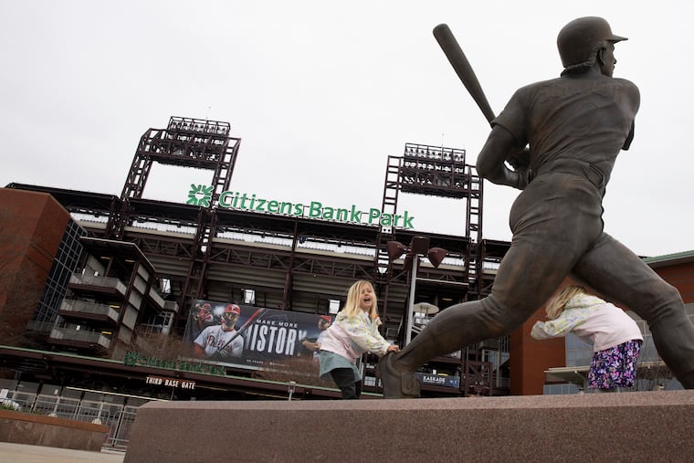 Ashley Talnack, 4, and Aubrey Talnack, 6, both of Chester Springs, pose near the Mike Schmidt statue at Citizens Bank Park on Wednesday, March 27, 2024.