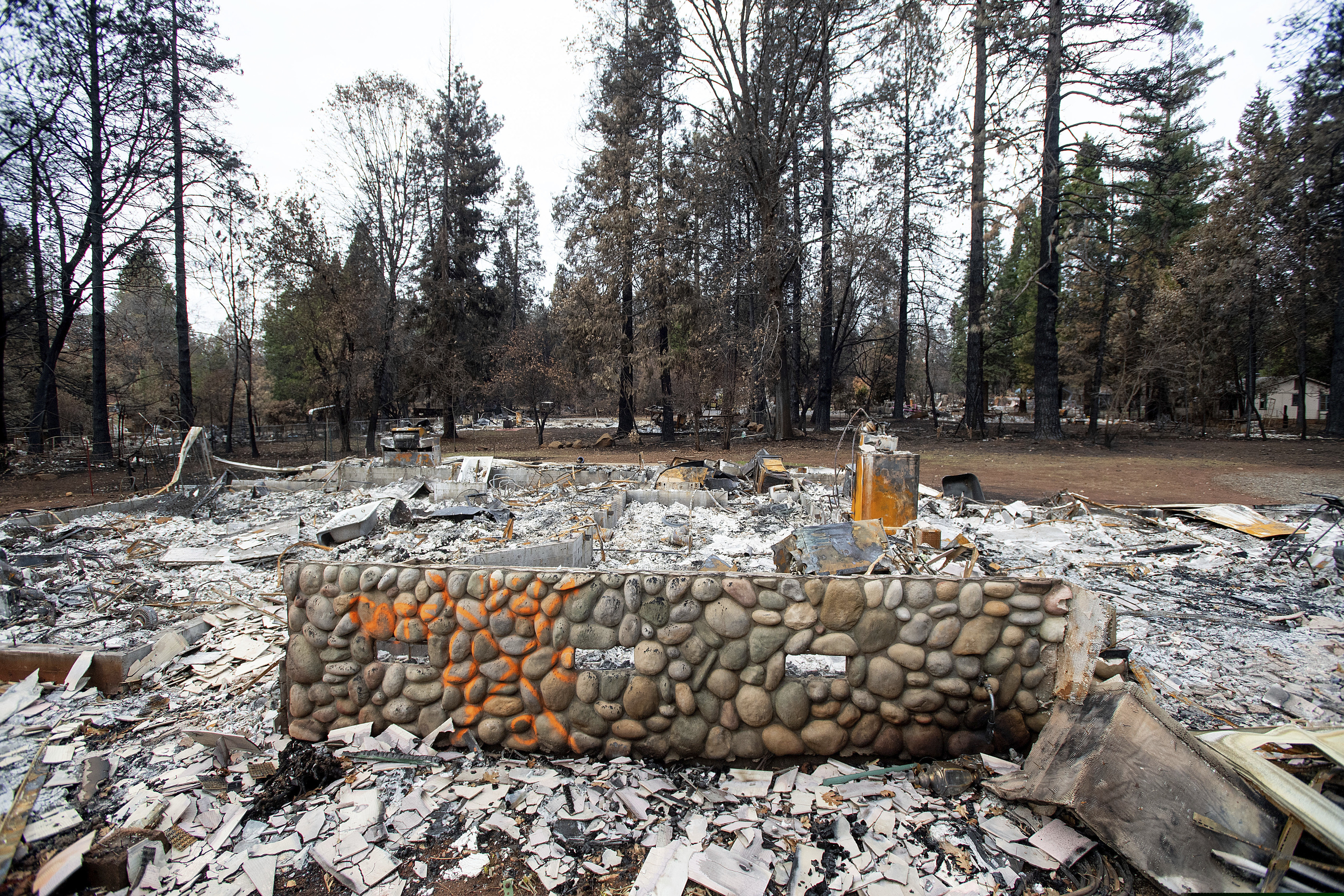 An exterior wall stands in front of the burned home of Patrick Holden and Nancy Barnes, Monday, Dec. 3, 2018, in Paradise, Calif. Holden and Barnes were listed as missing but are actually vacationing in Hawaii. (AP Photo/Noah Berger)
