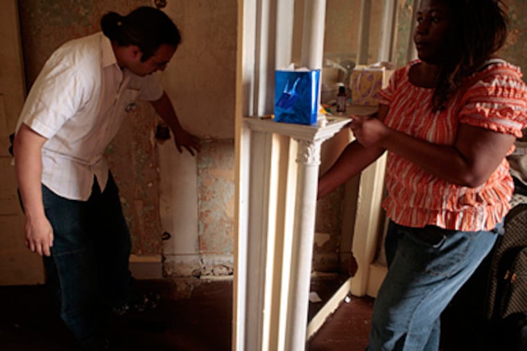 In Baltimore, Joe Cox, from the community organization ACORN, inspects an area of Eloise Litessy's front room where large quantities of lead paint were flaking away from the wall. (Dennis Drenner/MCT/File)