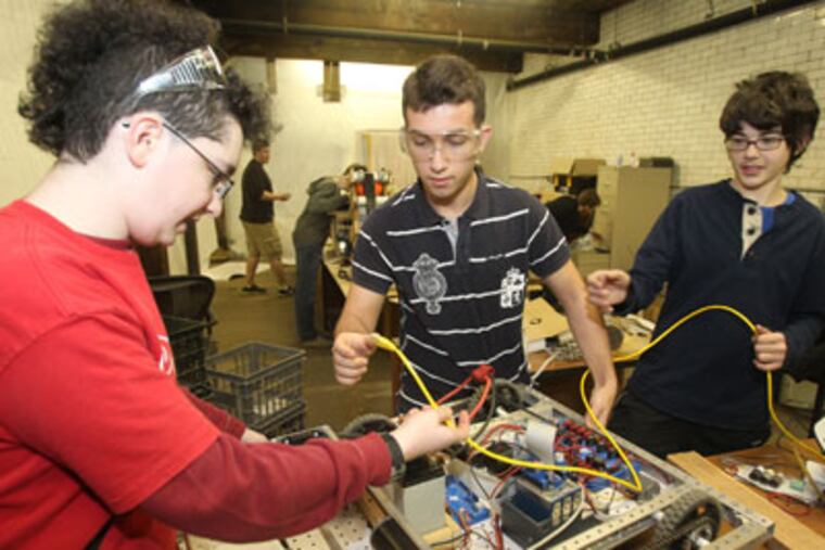 Massive budget cuts in the Philadelphia School District that ended robotics clubs in the fall at 15 district schools. The Masterman Atomic Robotics 4-H club created a regional team and opened up membership to students across the district. L-R: Emmett Neyman, Mikelanxhelo Novruzaj, and Max Fine, all Masterman students, work on the robots base. ( Charles Fox / Staff Photographer ) INEROBOTICS30P, 1/25/2012, HIGH SCHOOL ROBOTICS CLUBS, 3851 ARREN ST., PHILA., PA.