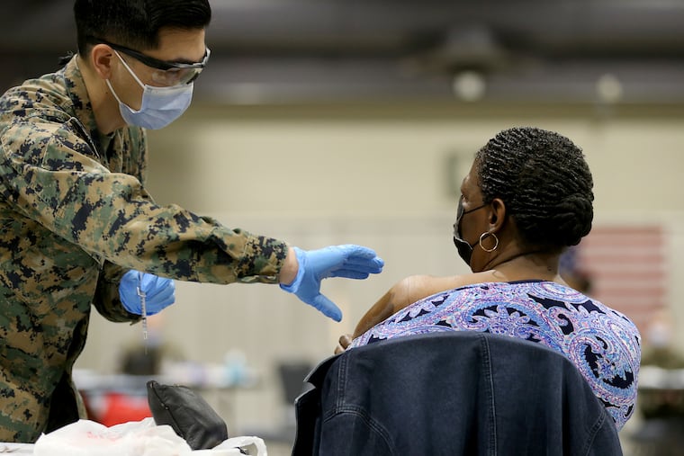 Joseph Delacruz (left) prepares to vaccinate Ava Rollins (right) at the FEMA-run vaccination site at the Pennsylvania Convention Center. Four thousand Pfizer vaccine doses were removed from cold storage earlier this week, and the city has administered about 1,000 so far. But with demand for vaccinations plateauing, the city faces the prospect of thousands of vaccine doses expiring before they can be used.