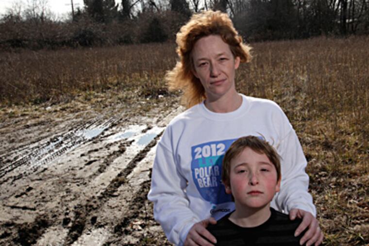 Catherine Cuffy and son Garrett, 8, at the Franklin Township site of a former thermometer factory where the now-demolished Kiddie Kollege day care once stood. Garrett, who attended there, has been diagnosed with ADHD. (Michael S. Wirtz / Staff Photographer)