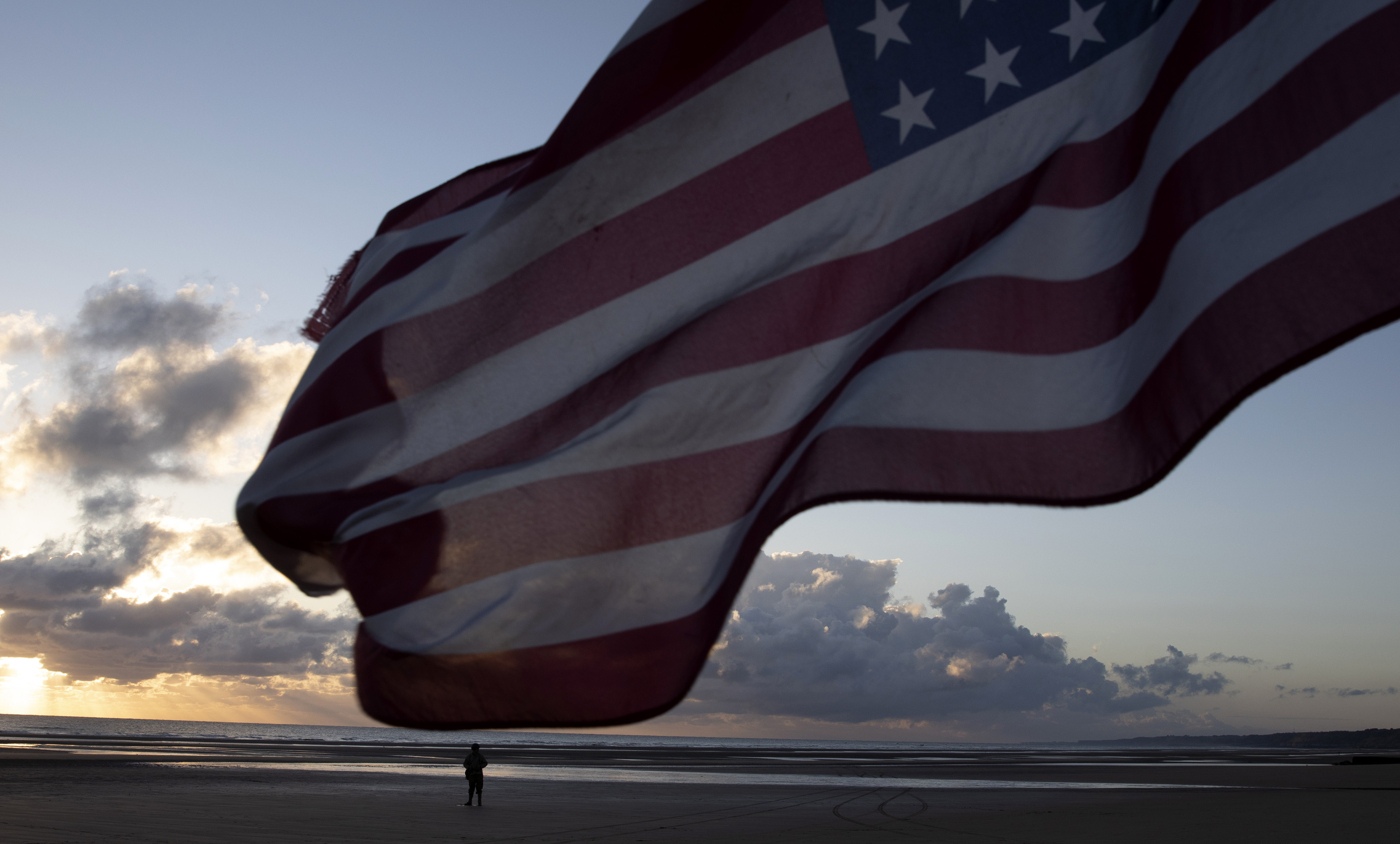 A man in a vintage US WWII uniform walks at sunrise prior to a D-Day 76th anniversary ceremony in Saint Laurent sur Mer, Normandy, France, Saturday, June 6, 2020. Due to coronavirus measures many ceremonies and memorials have been cancelled in the region with the exception of very small gatherings.