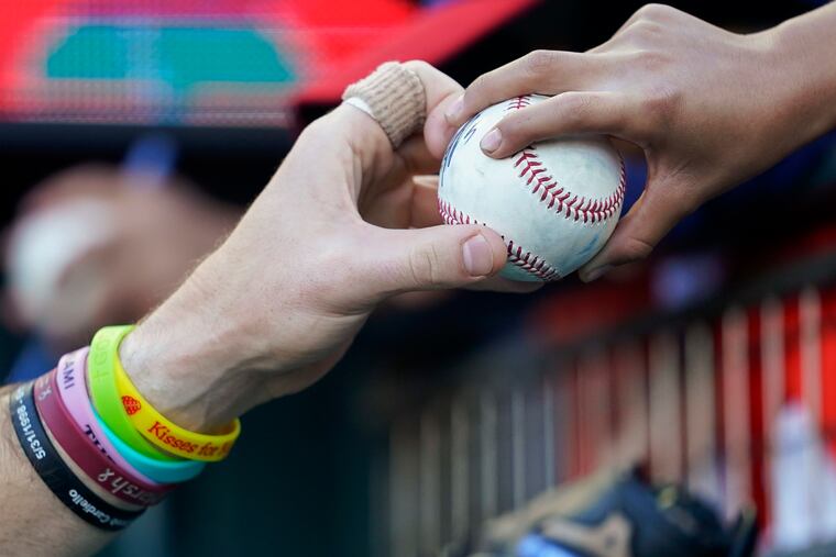 Phillies' Brandon Marsh (left) returns an autographed ball to a fan before the team's baseball game against the San Francisco Giants in San Francisco, Friday, Sept. 2, 2022.