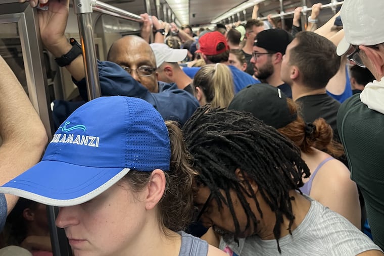 Sweltering runners wait on a stranded Broad Street subway car on the way to the Broad Street Run.