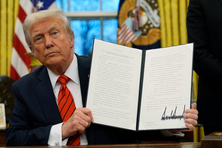 President Donald Trump holds up an executive order relating to the Foreign Corrupt Practices Act in the Oval Office at the White House on Monday, Feb. 10, 2025, in Washington.