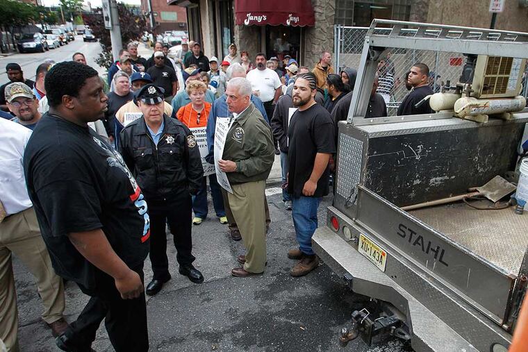 At left is an employee of the Post Brothers construction escorting a work vehicle on to the job site. Union workers were protesting the non-union job site on Monday. Unionized labor supporters and workers with Post Brothers the developers of a property at N. 12th St. and Wood gather at the job site on Monday morning May 21, 2012. Both sides of the fence were well represented with large guys. ( ALEJANDRO A. ALVAREZ / STAFF PHOTOGRAPHER )