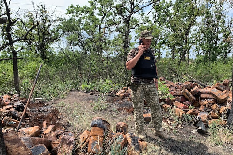 A Ukrainian field commander known as Major Andre examines piles of ammunition boxes that were carried by a Russian convoy that had been ambushed by Ukrainian troops on the frontlines near the village of Shevchenkove.