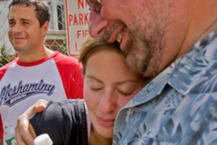 Fred Snyder comforts his newlywed daughter, Jamie Rongione, who was honeymooning in Guatemala when fire destroyed her home. Behind them is her husband, Scott.