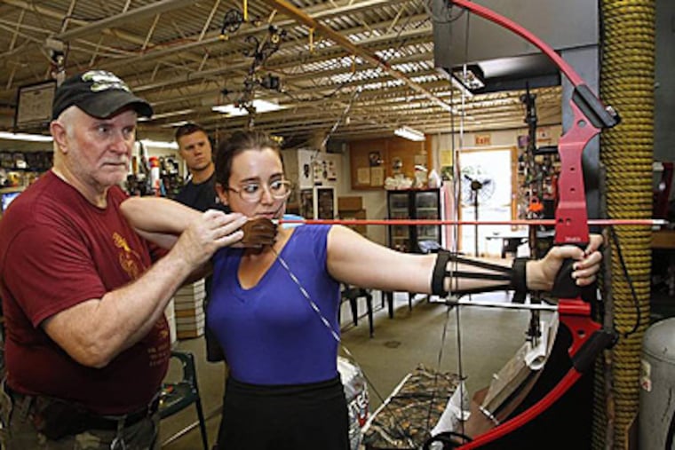 Molly Eichel gets tips from B&A Archery's Bill Arrow while Jonathan Papelbon looks on. (Alejandro A. Alvarez/Staff Photographer)