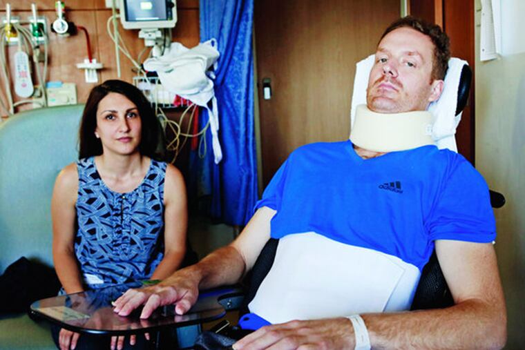 Eli Kulp in a New York hospital room with wife Marisa last week. Kulp, 37, who suffered a severe spinal cord injury when he was thrown about in the derailment at Frankford Junction, is now at a rehab facility in Atlanta. ANGEL CHEVRESTT