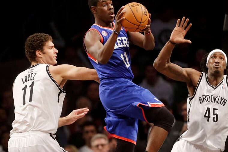Jrue Holiday is sandwiched by the Nets' Brook Lopez and Gerald Wallace as he looks for a teammate. Holiday led the 76ers with 24 points and nine assists. SETH WENIG / Associated Press
