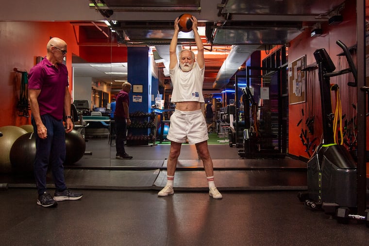 David Pallett, 77, of Philadelphia uses an eight-pound medicine ball to work out with Jim Hart, a personal trainer who specializes in working with older adults, at Optimal Sport 1315 in Center City.