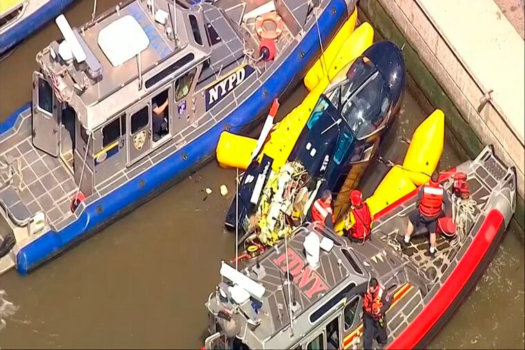 In this image made from video provided by WABC-TV, harbor units from the New York City police and fire departments work to secure a helicopter to the dock after it crashed in the Hudson River, Wednesday, May 15, 2019 in New York. WABC reports that the pilot was ok and that there were no passengers on the aircraft.