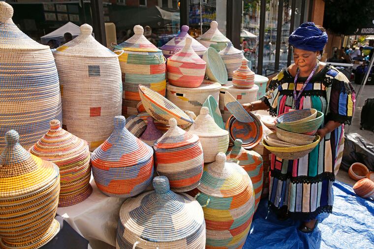 Zenabou Vouda arranges woven baskets from Senegal as she prepares her stall for visitors.
