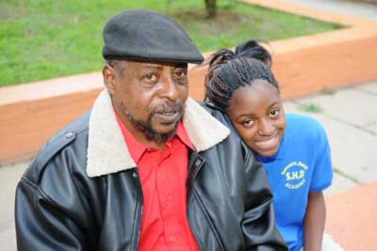 Mac Hicks (left) sits with his daughter Evon (right) in the courtyard
in front of their home. Hicks wants to send his daughter to one of the Philadelphia charter schools so that she can get a better education and stay away from violence. (Kriston J. Bethel / Staff Photographer)