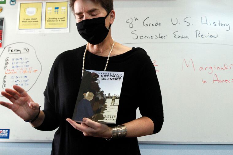 History teacher Wendy Leighton holds a copy of "They Called Us Enemy," about the internment of Japanese Americans, while speaking about being marginalized with her students at Monte del Sol Charter School on Dec. 3, 2021, in Santa Fe, N.M.