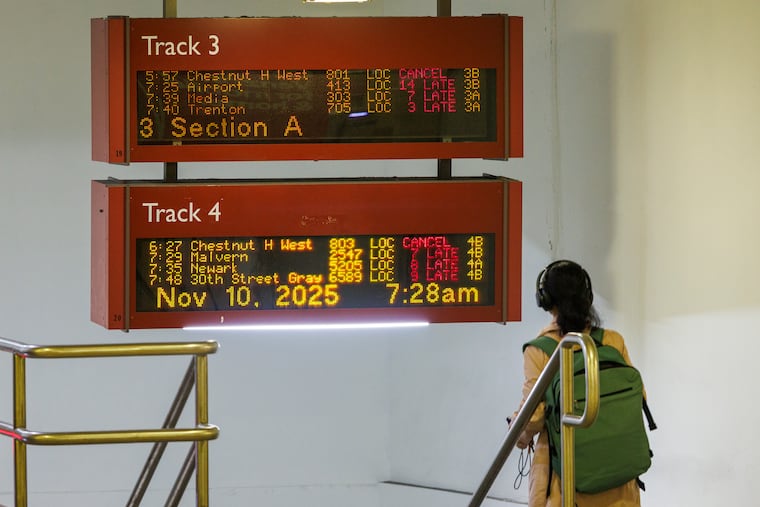 Commuter walking past schedule displays at Suburban Station on Monday, Nov. 10, 2025.