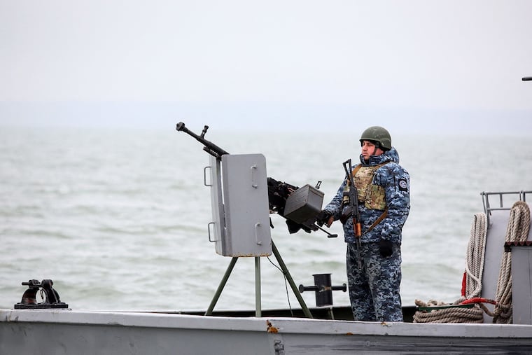 A serviceman standing guard as he boat patrols a water area of Ukraine's Black Sea port of Mariupol on Feb. 11.
