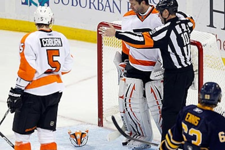 Brian Boucher looks down at his mask after knocking it off to stop play during a Sabres' power play. (Yong Kim/Staff Photographer)