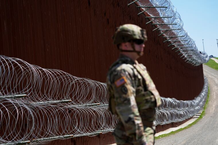 A member of the military stands in front of newly-installed concertina wire lining one of two border walls separating Mexico from the United States during a news conference on joint operations involving the military and the Border Patrol on March 21, 2025, in San Diego.