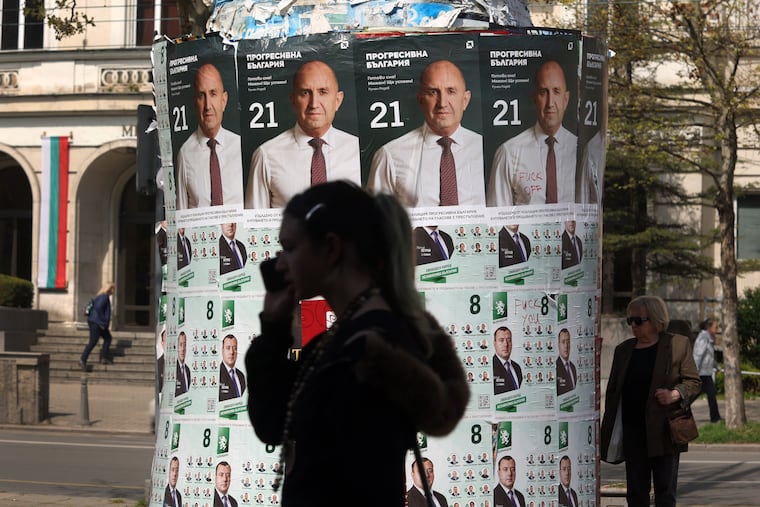 People pass posters of former President Rumen Radev in Sofia on Monday after Bulgaria's parliamentary election.