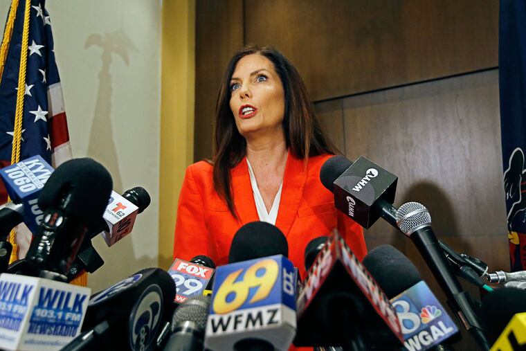 Surrounded by microphones, Pennsylvania Attorney General Kathleen G. Kane announces on Tuesday that she would not be seeking re-election as the state's Attorney General.