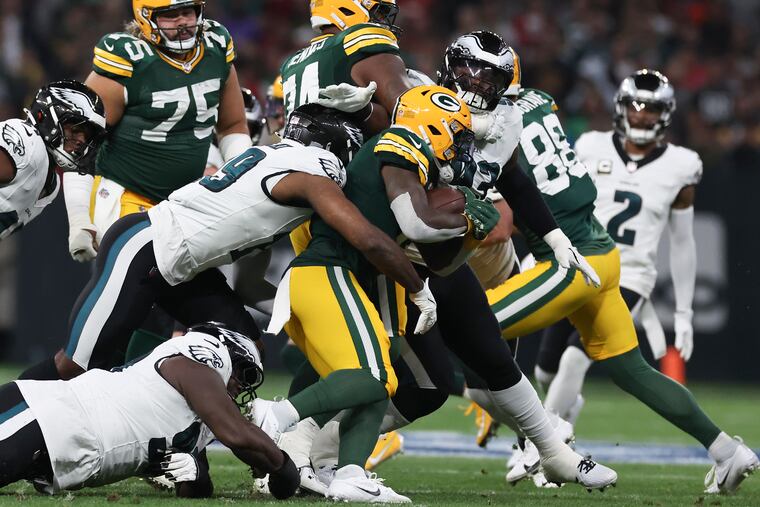 Eagles cornerback Darius Slay (right) looks on as linebacker Josh Sweat and defensive tackle Jordan Davis stop Green Bay Packers running back Josh Jacobs on Friday.