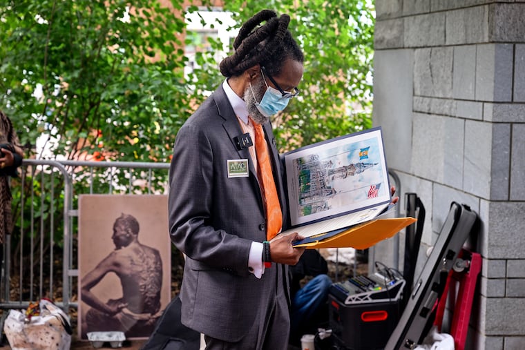 Attorney Michael Coard with the Avenging The Ancestors Coalition pauses backstage to look at a City Council proclamation after speaking at the President's House Site Thursday.
