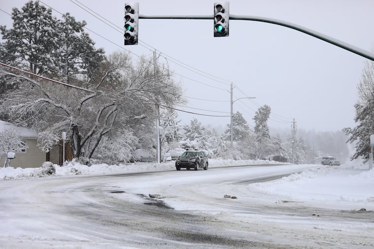 Commuters drive as the snow continues to fall north of downtown Flagstaff, Ariz., Friday. The storm is due to impact the East on Sunday and Monday.