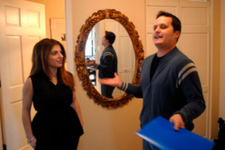 Real estate broker Jeffrey Block shows client Liza Tedeschi, of Center City, a two-bedroom home on South 17th Street. Buyers like condo owner Tedeschi are not put off by the market's current state. "I'm busier than I've ever been in the 27 years I've sold real estate," a local agent said.