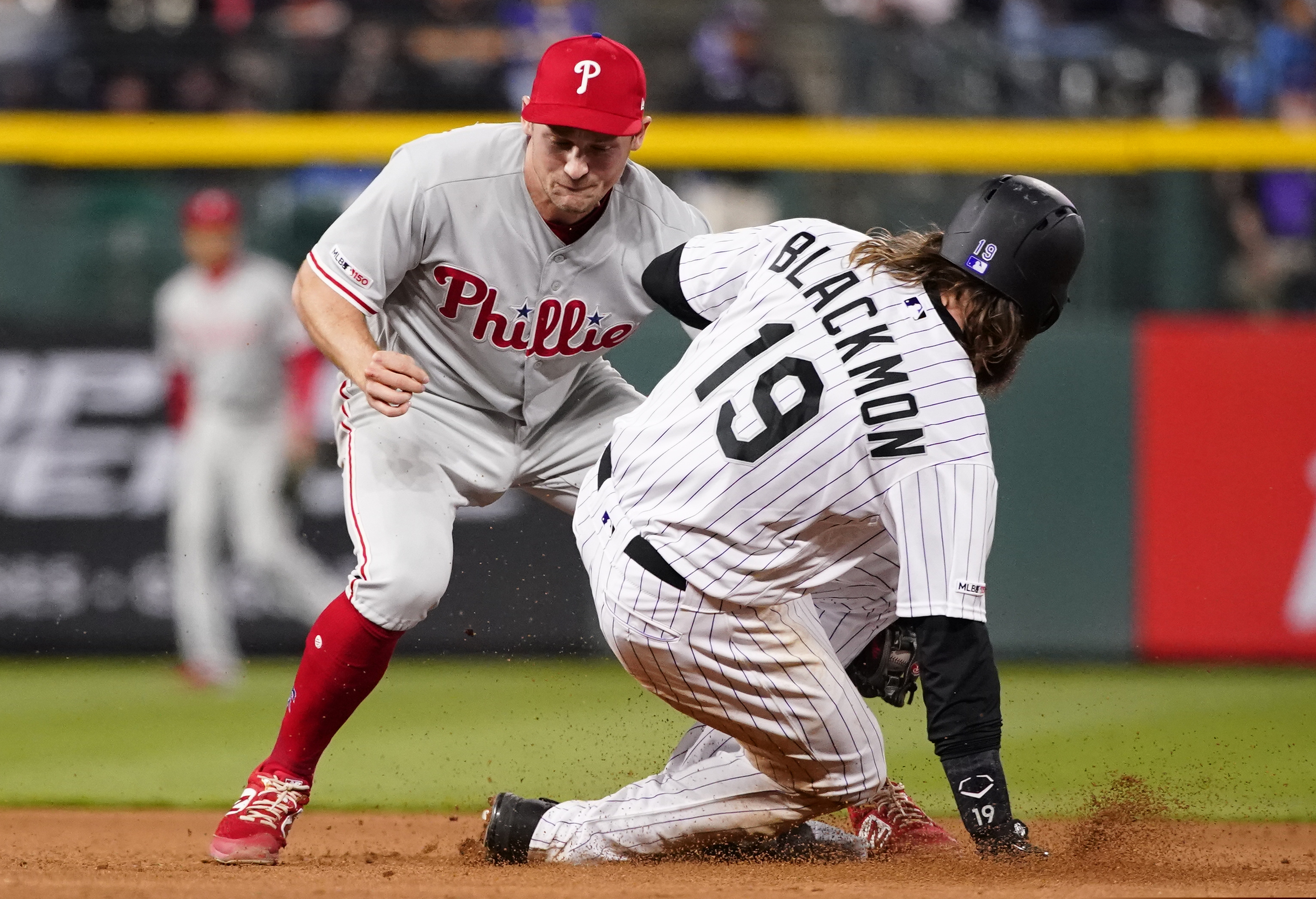 Philadelphia Phillies shortstop Phil Gosselin, left, tags out Colorado Rockies' Charlie Blackmon (19) on an attempted steal at second during the seventh inning of a baseball game Friday, April 19, 2019, in Denver. (AP Photo/Jack Dempsey)