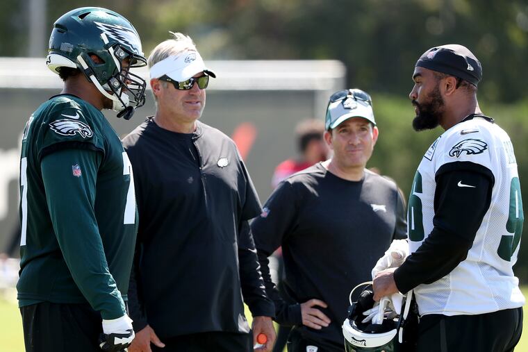 Andre Dillard (left) talks out an incident with Derek Barnett as Doug Pederson (second from left) and Howie Roseman watch.