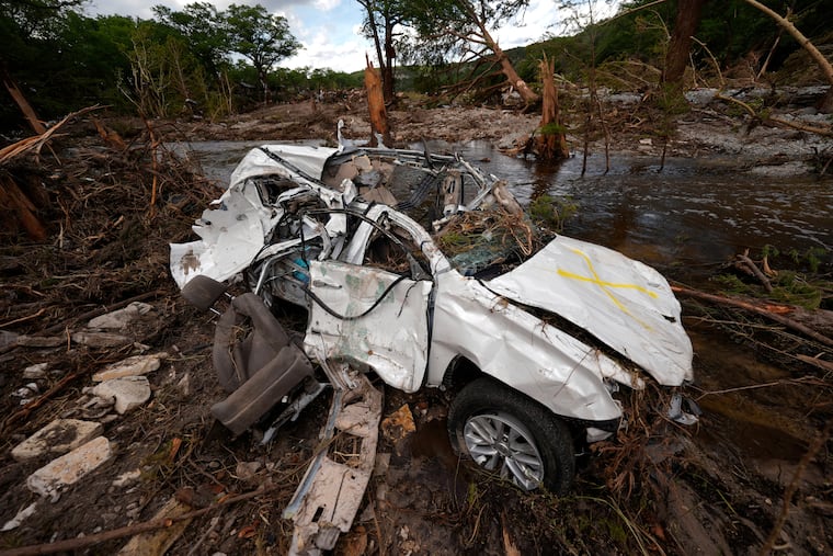 A destroyed vehicle sits next to the Guadalupe River in Hunt, Texas, on Wednesday after a flash flood swept through the area.