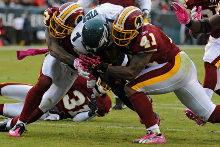 Michael Vick is sandwiched between Redskins' DeAngelo Hall (left) and Kareem Moore, suffering a chest injury on the play.