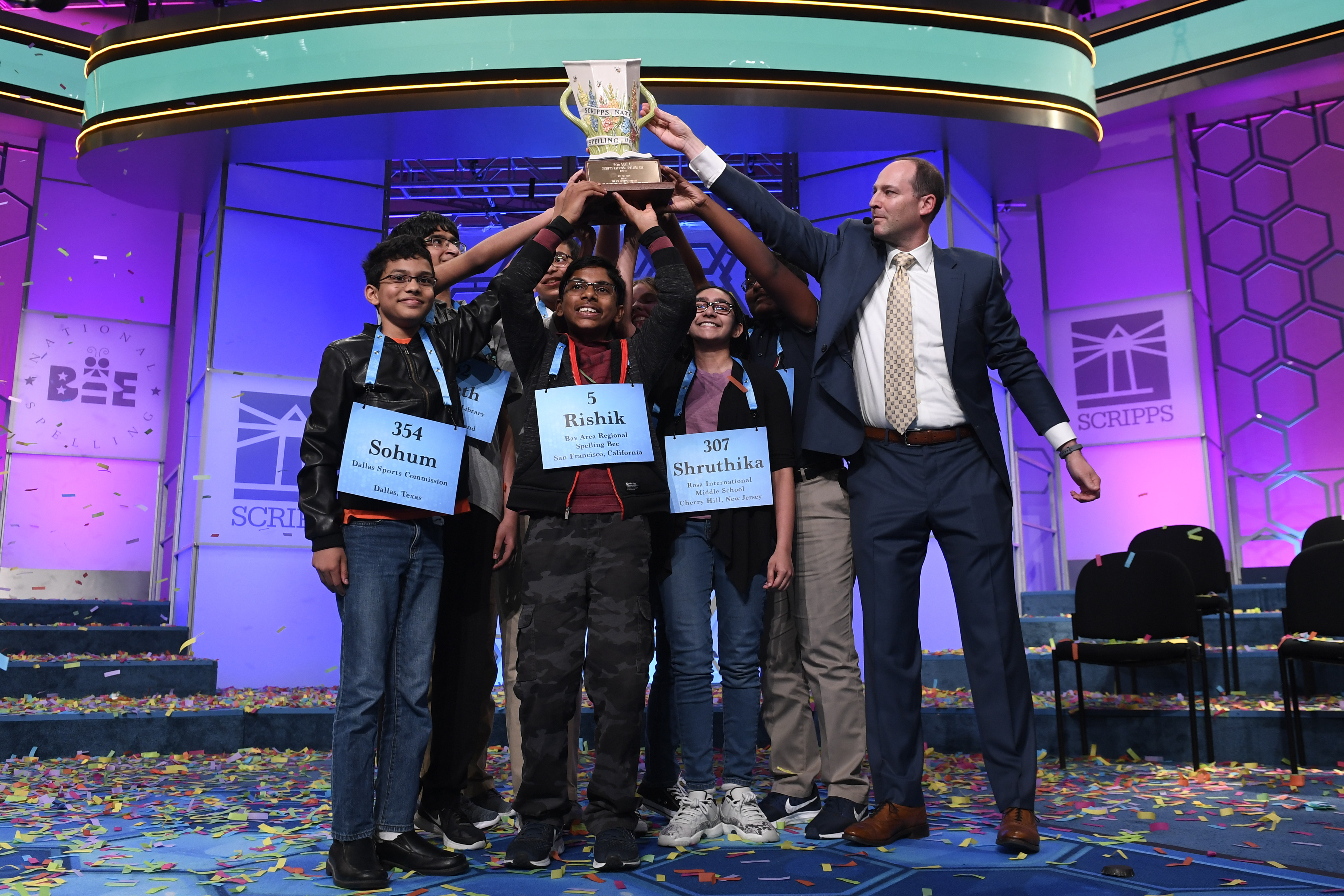 E.W. Scripps Company CEO Adam Symson, right, joins Sohum Sukhatankar (354), 13, of Dallas; Rishik Gandhasri (5), 13, of San Jose, Calif.; Shruthika Padhy (307), 13, of Cherry Hill, N.J., and the other winning spellers to hold the trophy at the end of the 2019 Scripps National Spelling Bee in Oxon Hill, Md., early Friday, May 31, 2019. The bee ended in an unprecedented 8-way championship tie after organizers ran out of challenging words.
