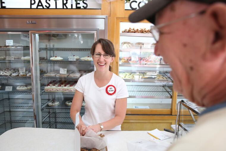 Jocelyn Wilson, left, smiles as she waits on longtime customer, Harry Beam, right, as Haegele's Bakery celebrates 85 years of business in the Mayfair section of Philadelphia on July 7, 2015. Wilson's grandmother worked at the shop. (DAVID MAIALETTI / Staff Photographer)
