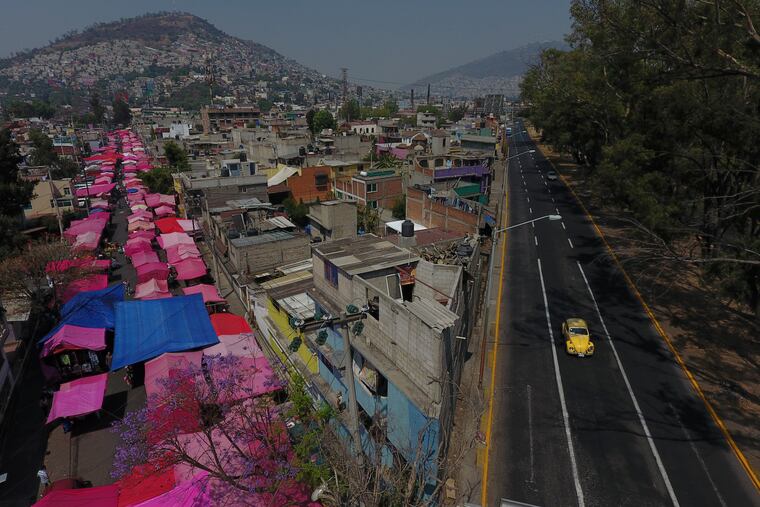 Pink tarps protect street stalls from the sun, as a reduced, but still active, street market takes place alongside a virtually deserted highway in Mexico City.