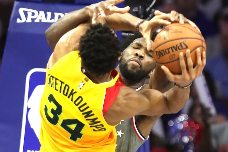 Joel Embiid, right, of the Sixers forces a jump ball with Giannis Antetokounmpo, left, of the Bucks at Wells Fargo Center during the 2nd half on April 4, 2019.